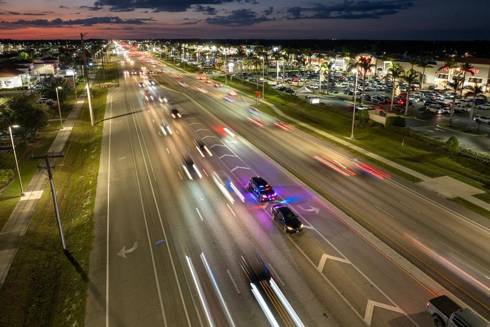 Aerial view of a police car pulling over a driver on a busy multilane road at night